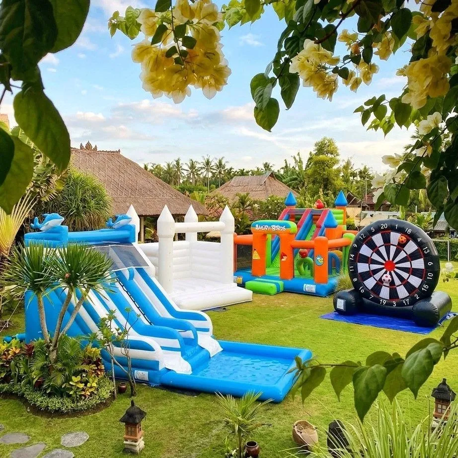 A white bouncy castle, a water slide, an Angry Birds inflatable and a giant football dart in a Bali garden